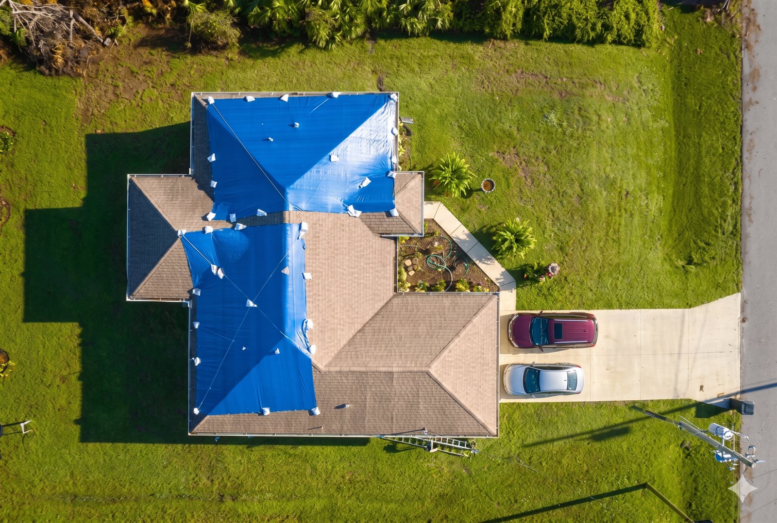 Aerial view of a Birmingham-metro home with emergency tarps over wind-damaged sections of the roof