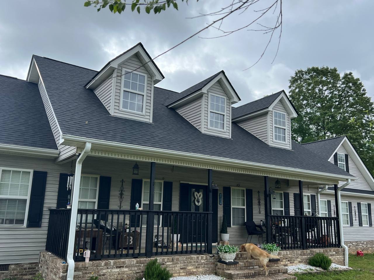 Completed dark dimensional-shingle roof on a Cape Cod home with a front porch